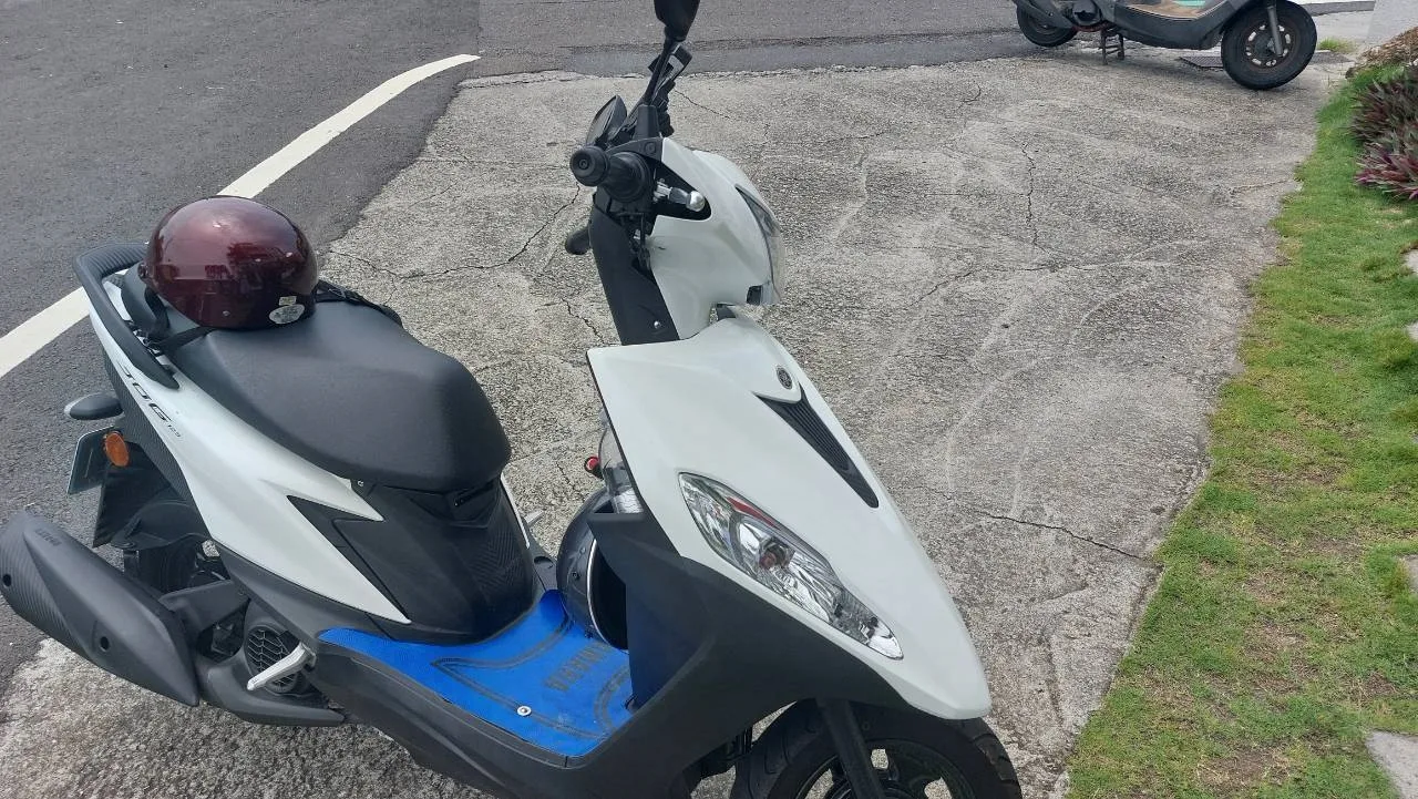 活力租車的白色Yamaha機車停在路旁,後座放有安全帽