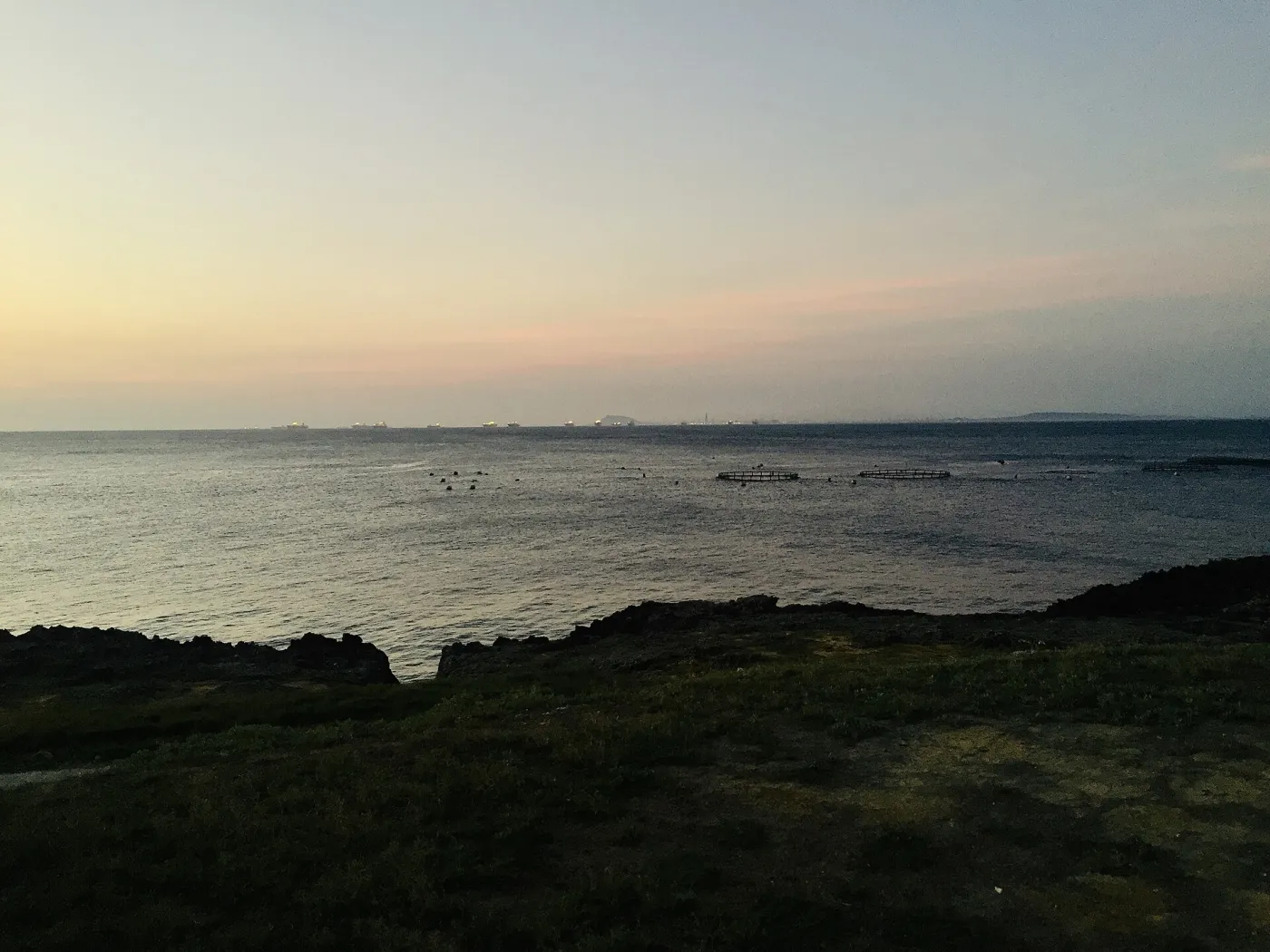 小琉球海灣的暮色，海面有箱網與浮球。